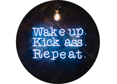 A neon sign saying "Wake up. Kick ass. Repeat.".