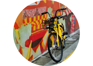Yellow bike leaning against colourful wall.