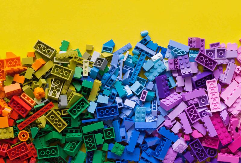 Lego blocks of various colours on a yellow table.
