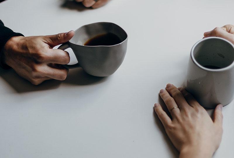 Top down shot of two people's hands holding coffee cups